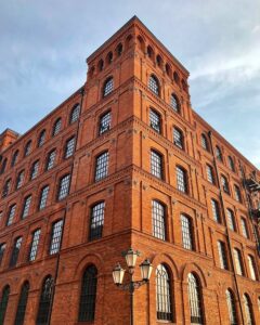 pexels-photo-14809372 Stunning view of a historic red brick building in Łódź, capturing urban architecture.